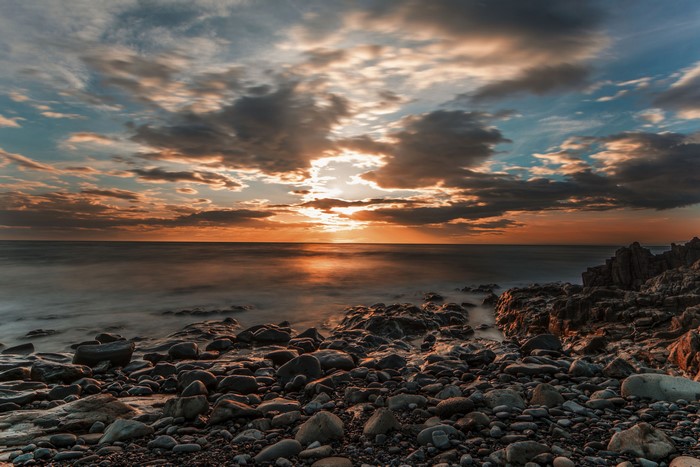 Sunset over rocky coast with dramatic clouds