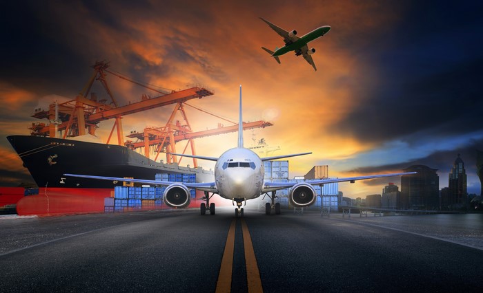 Cargo ship and airplanes at a port with city skyline