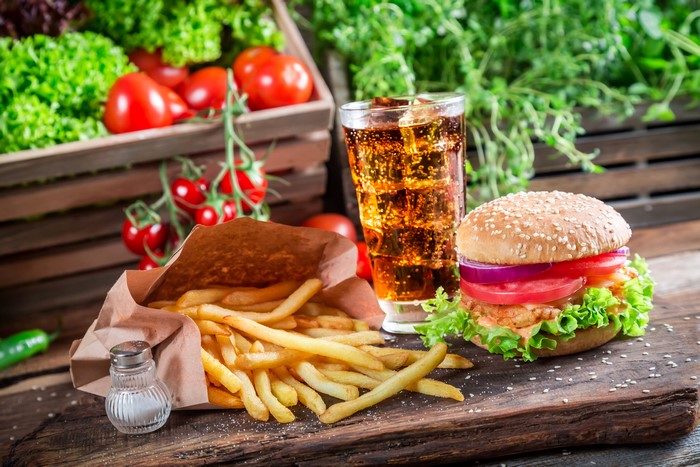 Hamburger, French fries, and soda with fresh vegetables