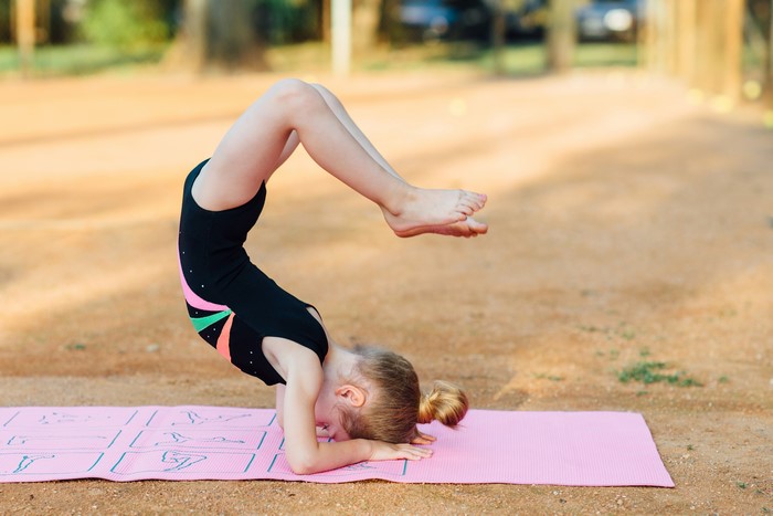 Young Girl Performing Gymnastics Pose on Mat