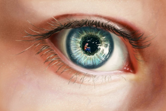 Close-up of a human eye with a person inside the pupil