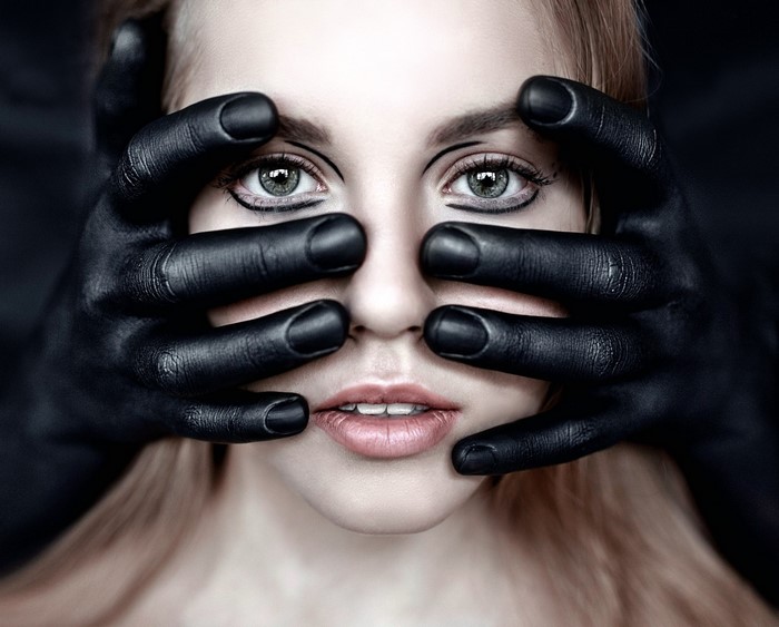 Woman's face covered by black hands