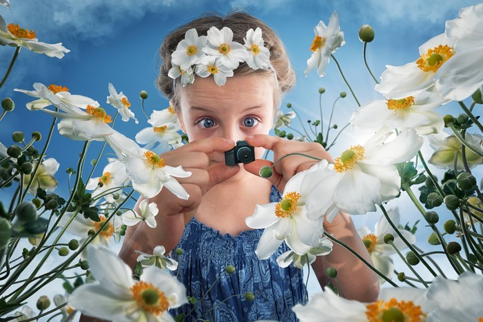 Girl with a flower crown holding a tiny camera