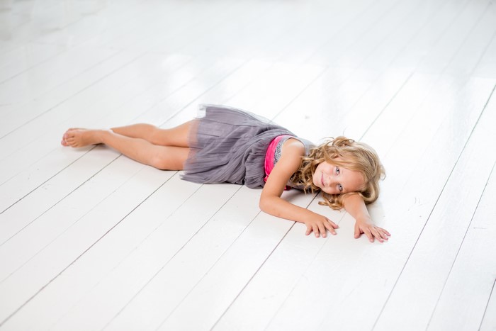 Young girl in a dress lying on a wooden floor