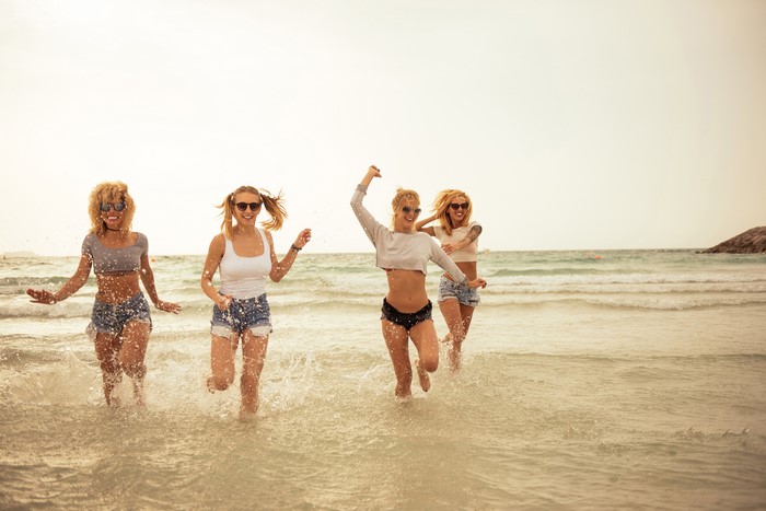 Four young women running in the sea