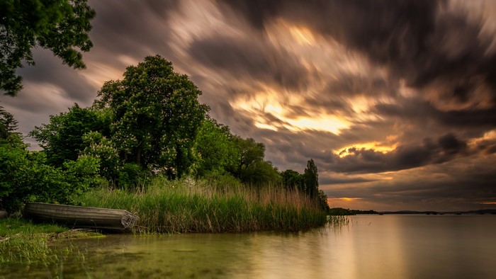 Boat on the shore of a lake with dramatic clouds