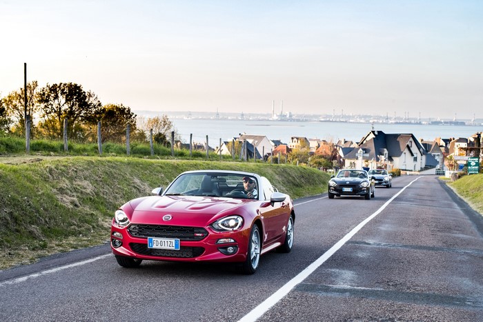 Red Fiat 124 Spider Cabriolet driving on a coastal road