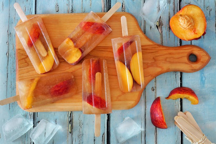 Peach popsicles on a wooden cutting board
