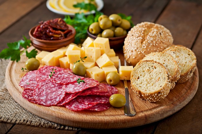 Charcuterie board with sausage, cheese, olives, and bread