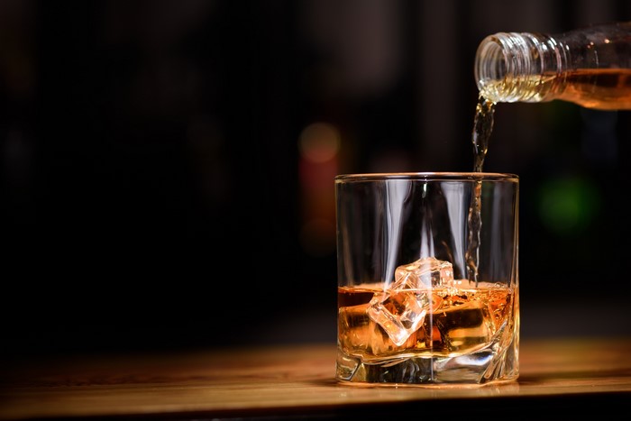 Whisky being poured into a glass with ice