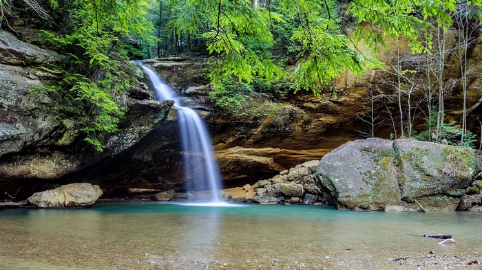 Waterfall cascading into a turquoise pool in a forest
