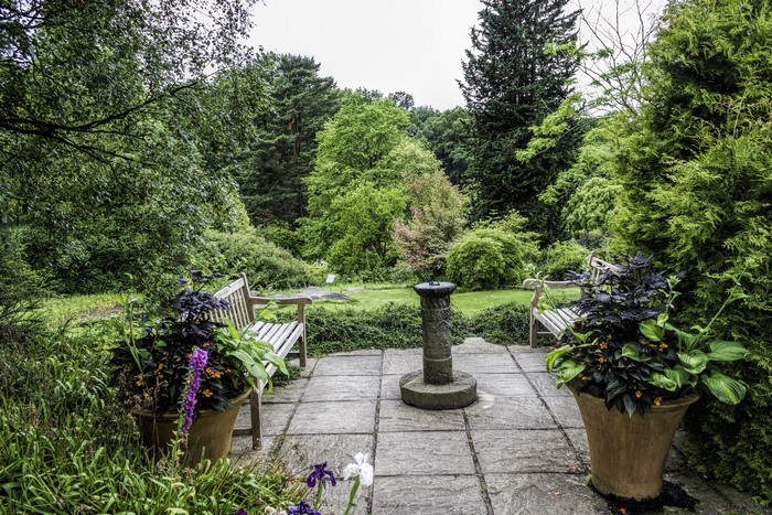 Garden benches and stone pedestal in a botanical garden