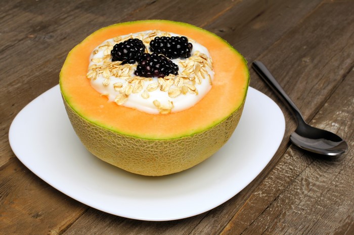 Cantaloupe half filled with yogurt, blackberries, and oats