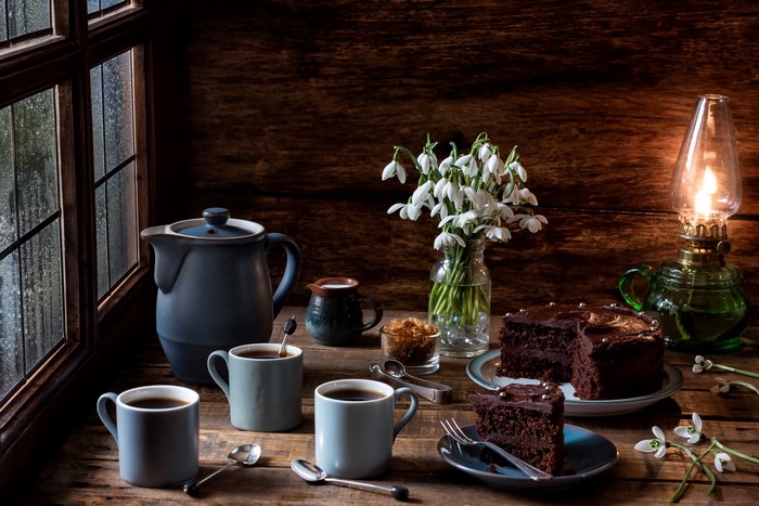 Still-life with coffee, cakes, snowdrops, and kerosene lamp