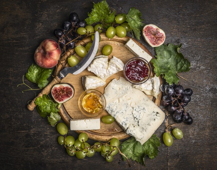 Cheese board with grapes, figs, jam, and peach