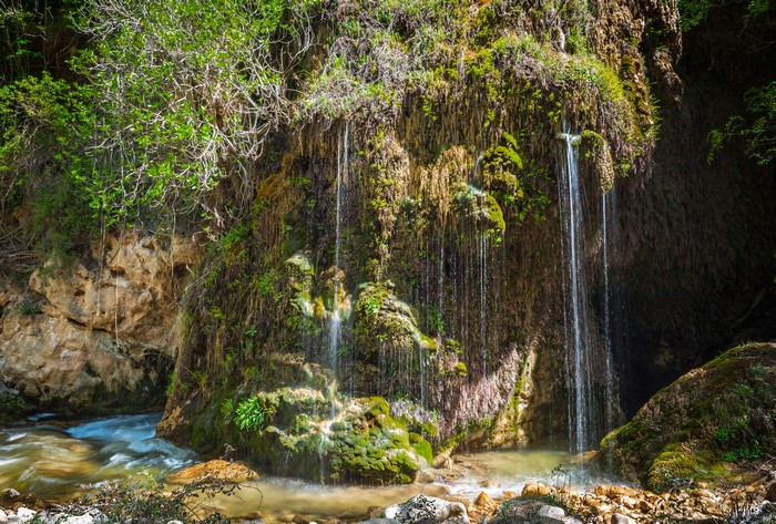 Waterfalls cascading over a moss-covered crag