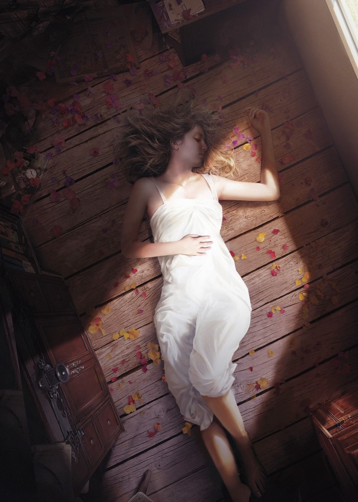 Woman sleeping on wooden floor with flower petals