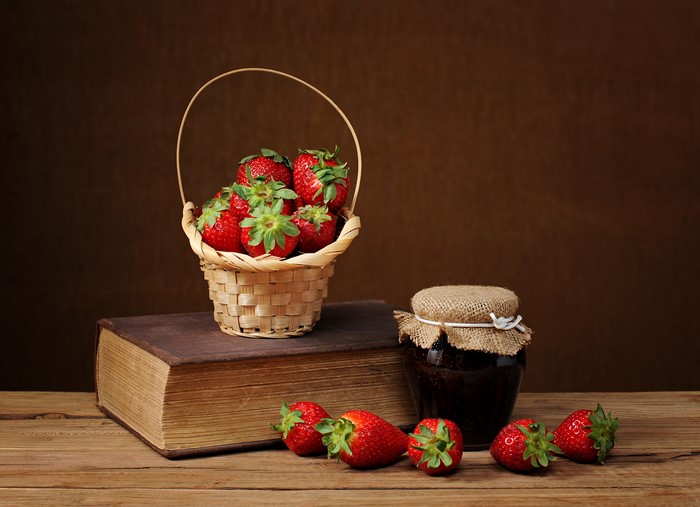 Strawberries in a basket on a book with jam