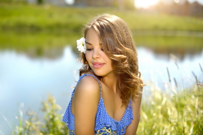 Brown haired girl with flower in hair by lake