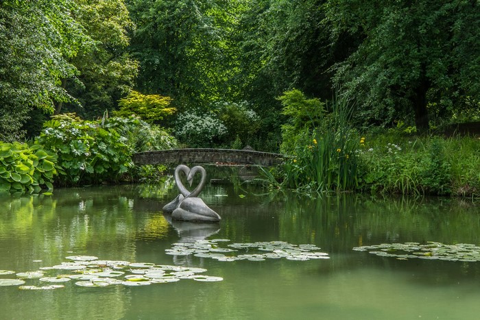 Swan sculptures in a pond with a bridge in Wiltshire, England