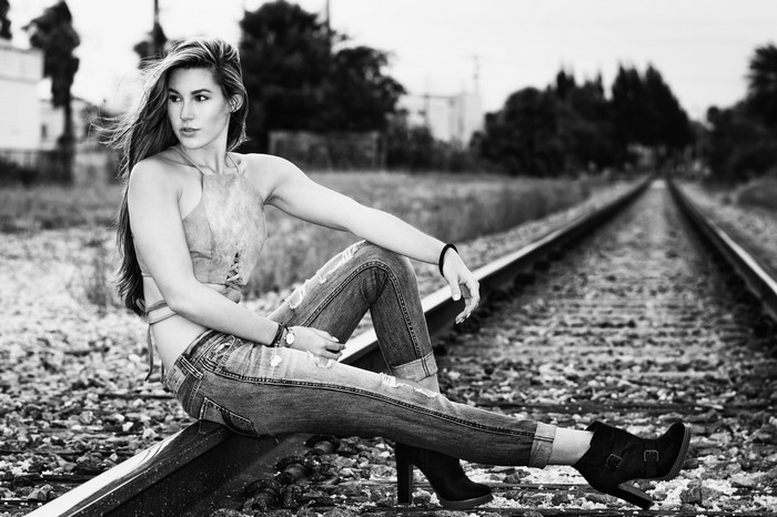 Woman sitting on railroad tracks