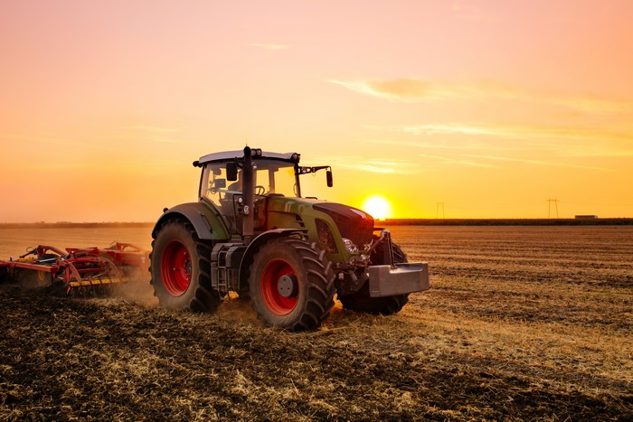 Tractor plowing a field at sunset