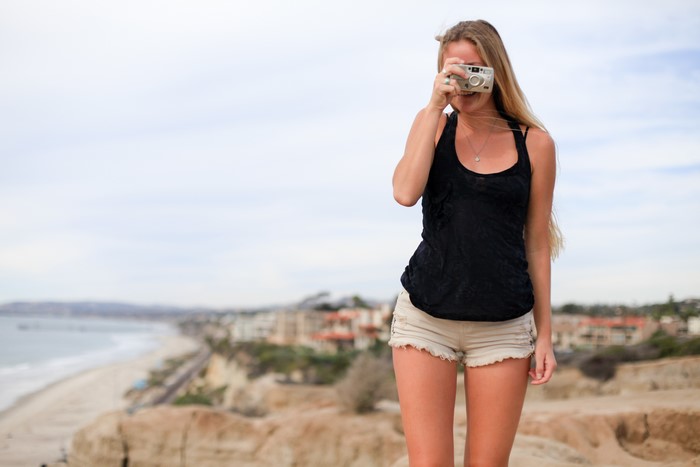 Woman with camera on cliff overlooking beach