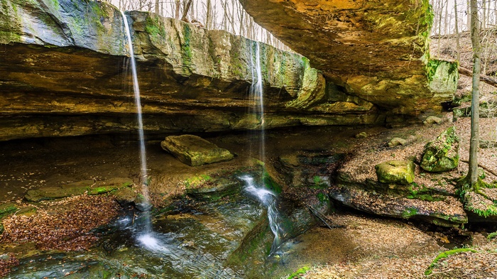 Waterfall cascading over a rock overhang in a forest