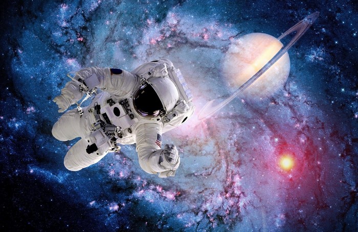 Astronaut in front of a ringed planet and nebula