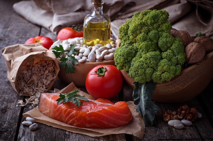 Still-life of salmon, vegetables, beans, nuts, and oil
