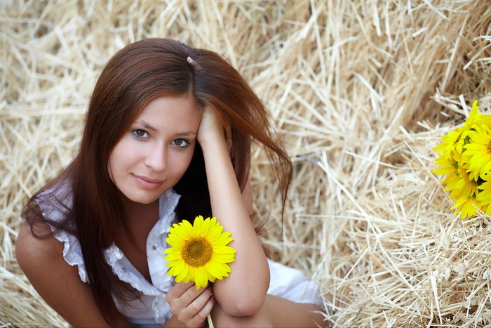 Young woman with sunflowers in hay
