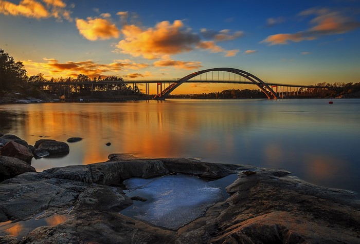 Bridge over water at sunset with clouds and rocks