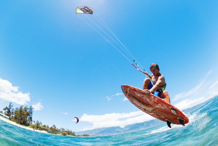 Man kitesurfing and jumping over the ocean waves