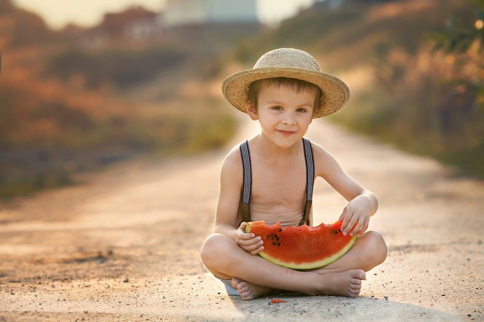 Boy in straw hat eating watermelon