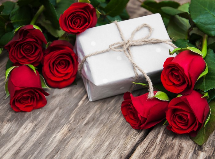 Red roses and a gift box on wooden planks