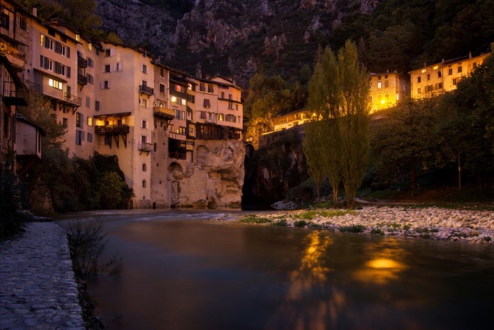 Houses on a cliff overlooking a river at night in Pont en Royans, France