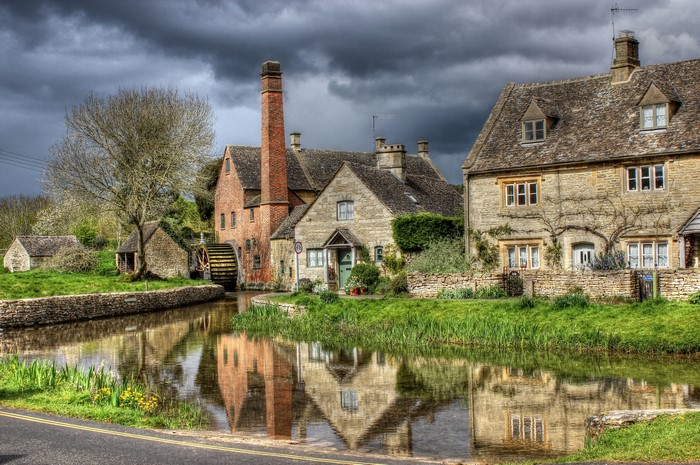 Old mill and houses by a river in the Cotswolds, England