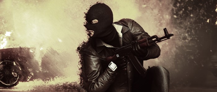 Man in mask with assault rifle near burning car