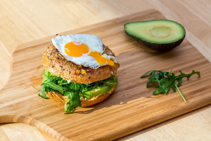 Fried egg sandwich with avocado on cutting board