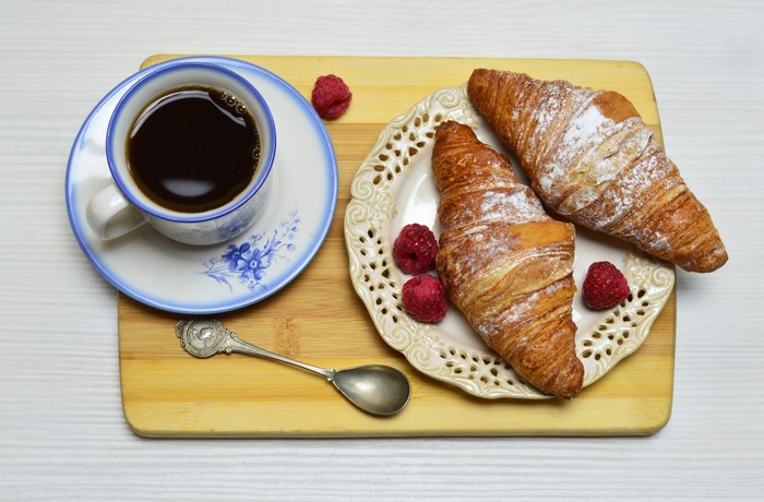 Croissant, Coffee, Raspberry, and Spoon on Cutting Board
