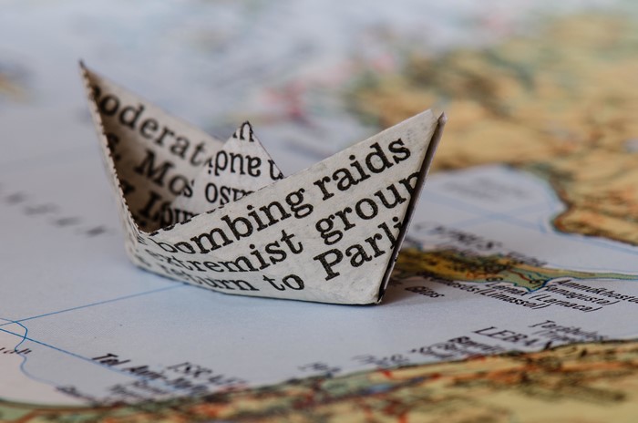 Paper boat made of newspaper on a map
