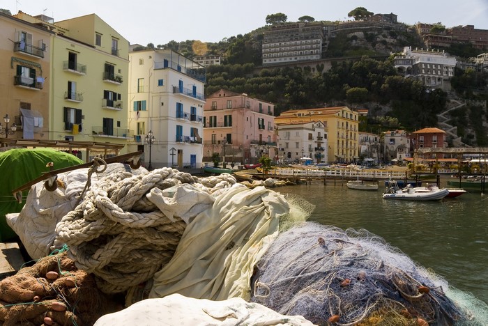 Fishing nets and ropes in a harbor with buildings on a hill in Sorrento, Italy