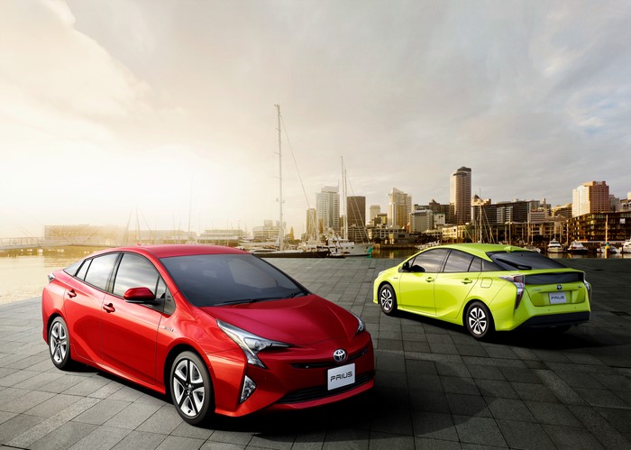 Two Toyota Prius cars by the water with city skyline