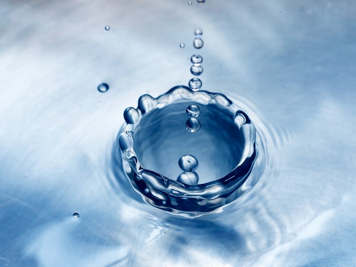 Water drops creating ripples on a blue surface