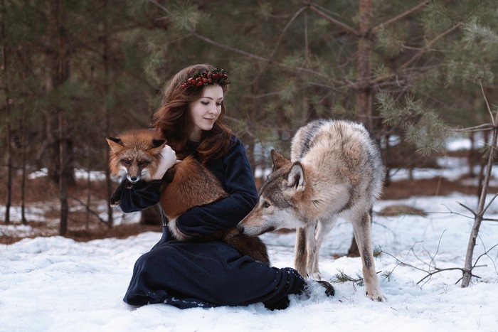 Girl with fox and wolf in snowy forest