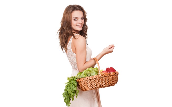 Woman holding a wicker basket with vegetables and fruits