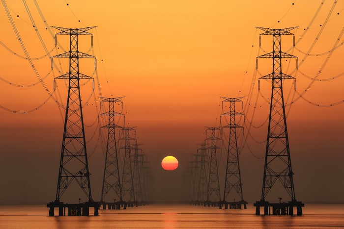 Power lines at sunset over water