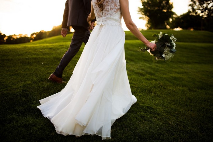 Bride and Groom walking on grass with bouquet