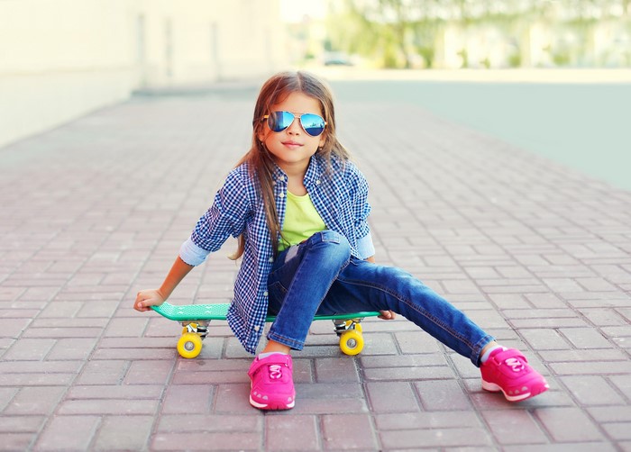 Girl in sunglasses sitting on a skateboard