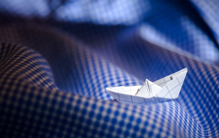 Origami paper boat on blue checkered fabric